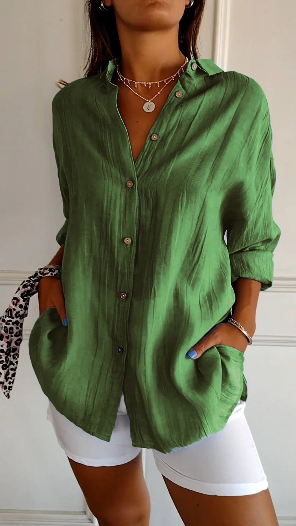 Chemise verte en lin pour femme, manches longues, boutons en bois, portée avec un pantalon blanc. Mode décontractée, tendance printemps-été.