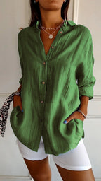 Chemise verte en lin pour femme, manches longues, boutons en bois, portée avec un pantalon blanc. Mode décontractée, tendance printemps-été.