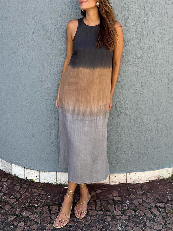Robe longue dégradée femme, sans manches, tons noir, marron et gris, portée avec sandales dorées, devant un mur texturé gris.