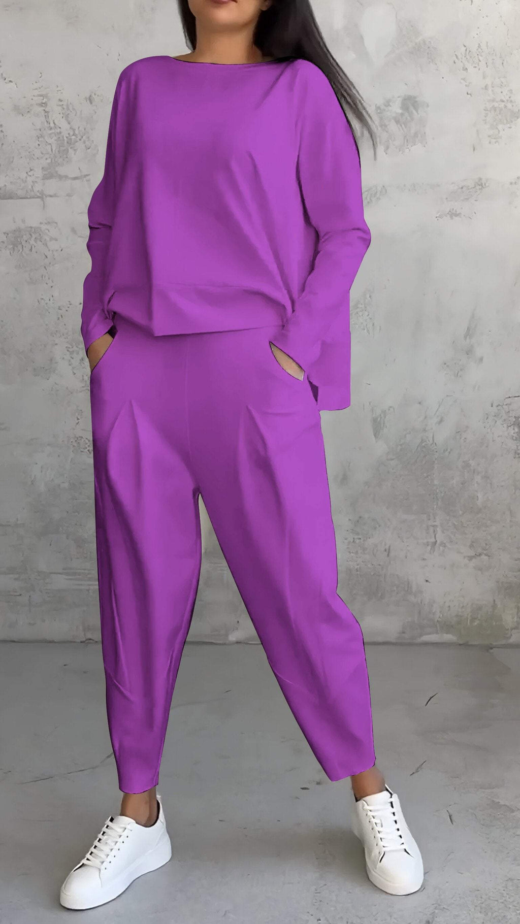 Femme portant un ensemble violet ample avec des poches, composé d'un haut à manches longues et d'un pantalon, assorti de baskets blanches.