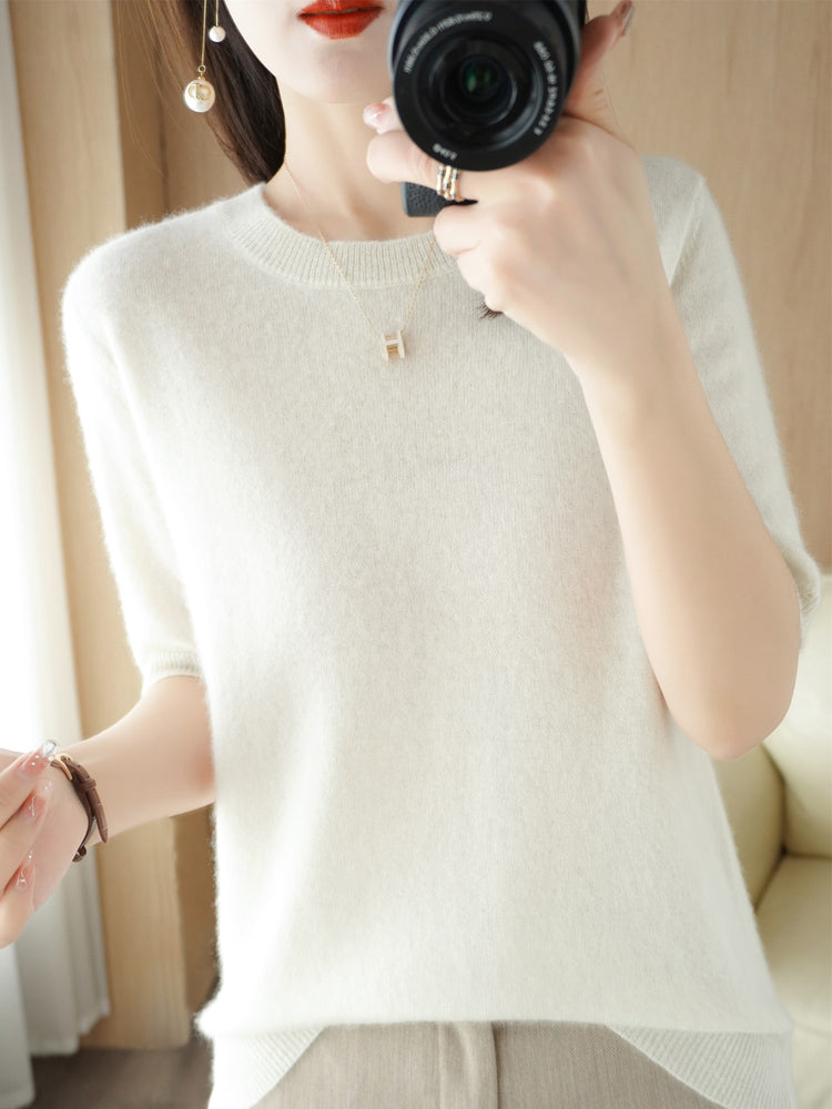 Femme portant un pull en cachemire blanc, photographiant avec un appareil photo. Mode élégante, style minimaliste, accessoires discrets.