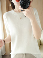 Femme portant un pull en cachemire blanc, photographiant avec un appareil photo. Mode élégante, style minimaliste, accessoires discrets.