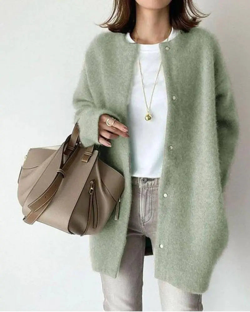 Femme portant un cardigan vert en laine, t-shirt blanc, jean gris, sac à main beige; mode automne-hiver, style décontracté chic.
