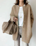 Femme portant un cardigan beige en laine, t-shirt blanc, jean gris, avec un sac à main beige. Mode automne, style décontracté chic.