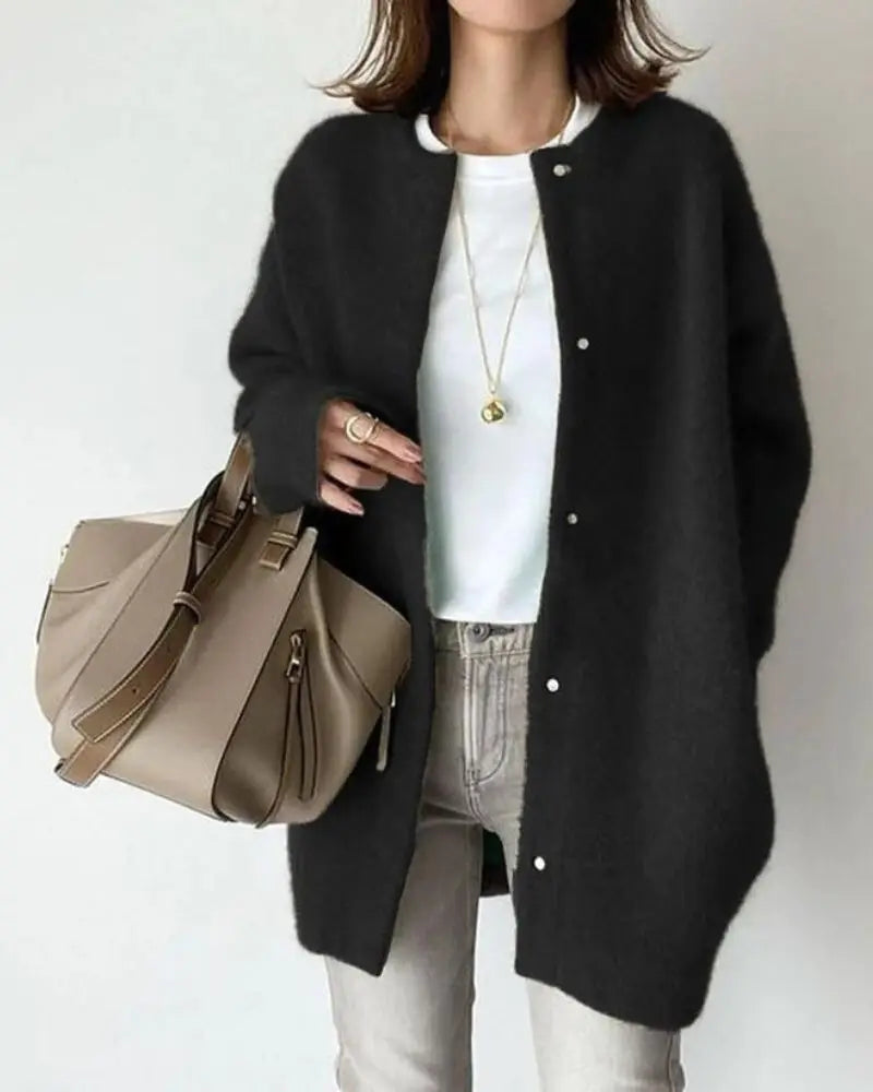 Femme portant un cardigan noir, t-shirt blanc, jean gris, sac à main beige; mode automne chic, tenue décontractée élégante, accessoires tendance.