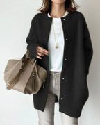 Femme portant un cardigan noir, t-shirt blanc, jean gris, sac à main beige; mode automne chic, tenue décontractée élégante, accessoires tendance.