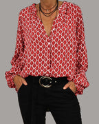 Chemisier rouge à motifs géométriques blancs, manches longues, col en V, porté avec un pantalon noir et ceinture, style décontracté et élégant.