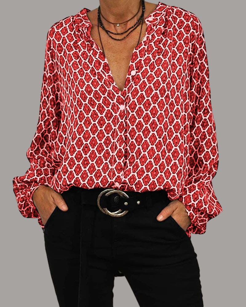 Chemisier rouge à motifs géométriques blancs, manches longues, col en V, porté avec un pantalon noir et ceinture, style décontracté et élégant.