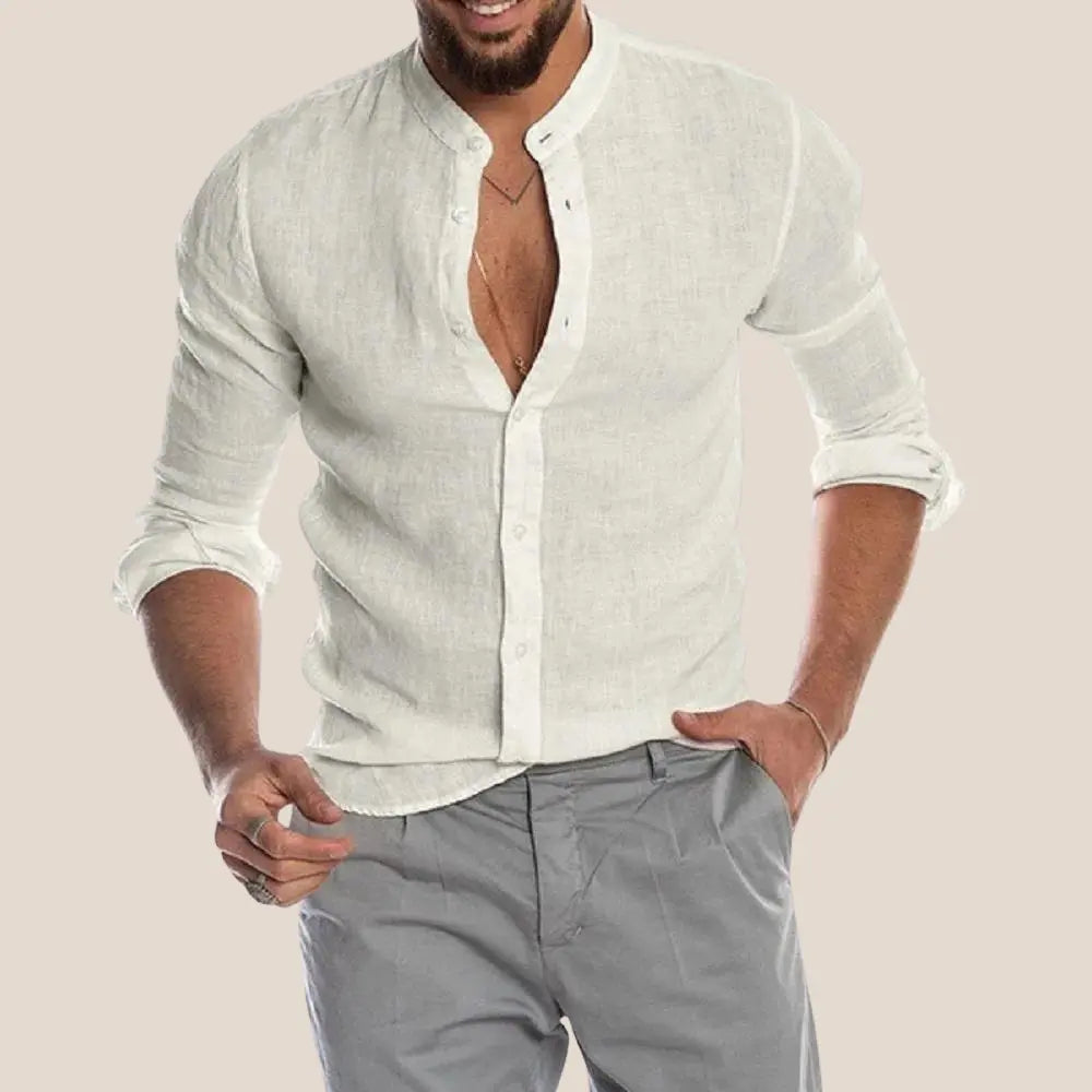 Homme portant une chemise en lin blanc à col mao, manches retroussées, avec un pantalon gris. Mode masculine élégante et décontractée.