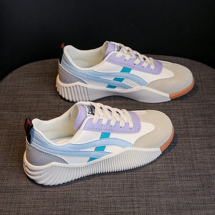 Chaussures de sport blanches et grises avec accents violets et bleus, semelle épaisse, posées sur un fond gris. Sneakers tendance pour femmes.