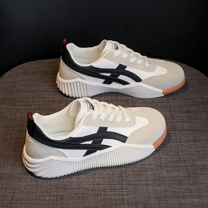 Chaussures de sport blanches et noires sur fond gris, design moderne avec semelle épaisse texturée, idéales pour la mode urbaine et le confort.