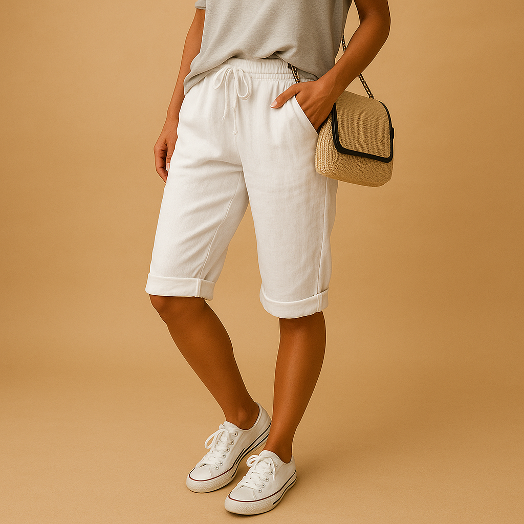 Femme portant un short blanc en lin, t-shirt gris, baskets blanches et sac en osier. Mode estivale décontractée, tenue élégante et confortable.