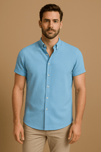 Homme portant une chemise bleue à manches courtes sur fond beige. Mode masculine, chemise élégante, tenue décontractée.