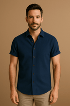 Homme portant une chemise bleue à manches courtes sur fond beige. Mode masculine élégante, style décontracté, chemise boutonnée tendance.