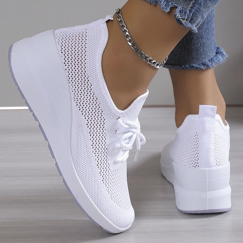 Baskets blanches à plateforme, design en maille respirante, portées avec un jean et un bracelet chaîne argenté. Chaussures mode femme tendance.