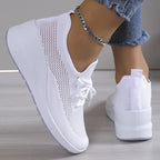 Baskets blanches à plateforme, design en maille respirante, portées avec un jean et un bracelet chaîne argenté. Chaussures mode femme tendance.