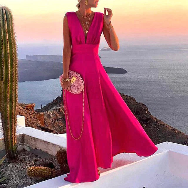 Robe longue rose élégante portée par une femme au coucher du soleil, avec vue sur la mer et cactus, style chic et glamour, mode estivale.
