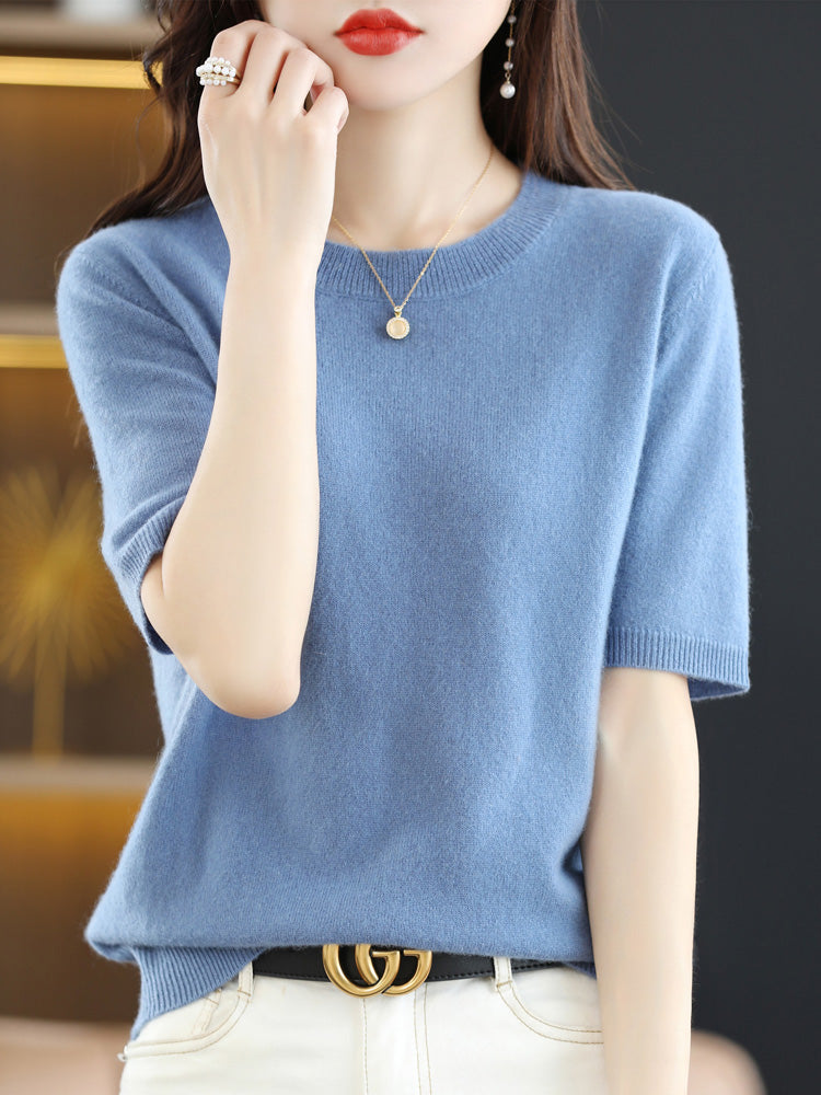 Femme portant un pull bleu en cachemire, collier doré et ceinture noire avec boucle dorée. Mode élégante, tenue chic, style automne-hiver.