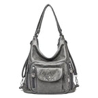 Sac à main en cuir gris avec bandoulière, poches zippées et bouton-pression. Élégant et pratique pour femme, idéal pour un usage quotidien.