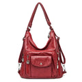 Sac à main rouge en cuir synthétique avec bandoulière réglable, poches zippées et détails métalliques. Accessoire mode femme élégant et pratique.