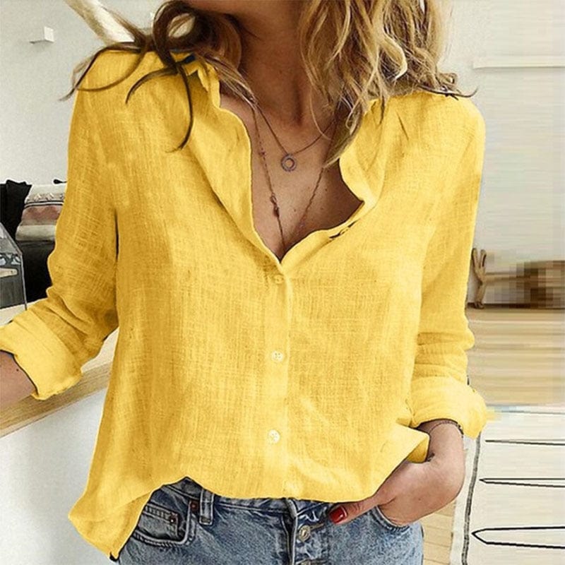 Femme portant une chemise en lin jaune vif, manches retroussées, associée à un jean décontracté, dans un intérieur moderne et lumineux.