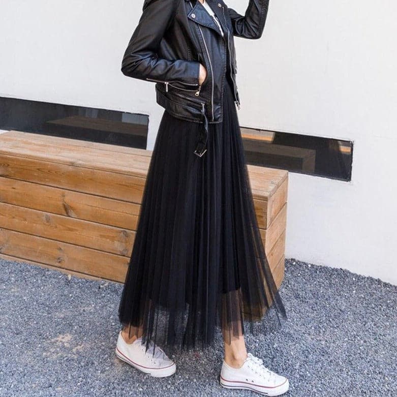 Veste en cuir noir sur robe longue en tulle noir, baskets blanches, style urbain chic, mode féminine moderne, look décontracté tendance.