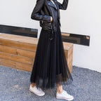 Veste en cuir noir sur robe longue en tulle noir, baskets blanches, style urbain chic, mode féminine moderne, look décontracté tendance.