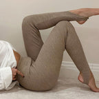 Femme portant un legging côtelé beige, allongée sur le sol, chemise blanche. Mode féminine, confort, style décontracté, tendance automne.