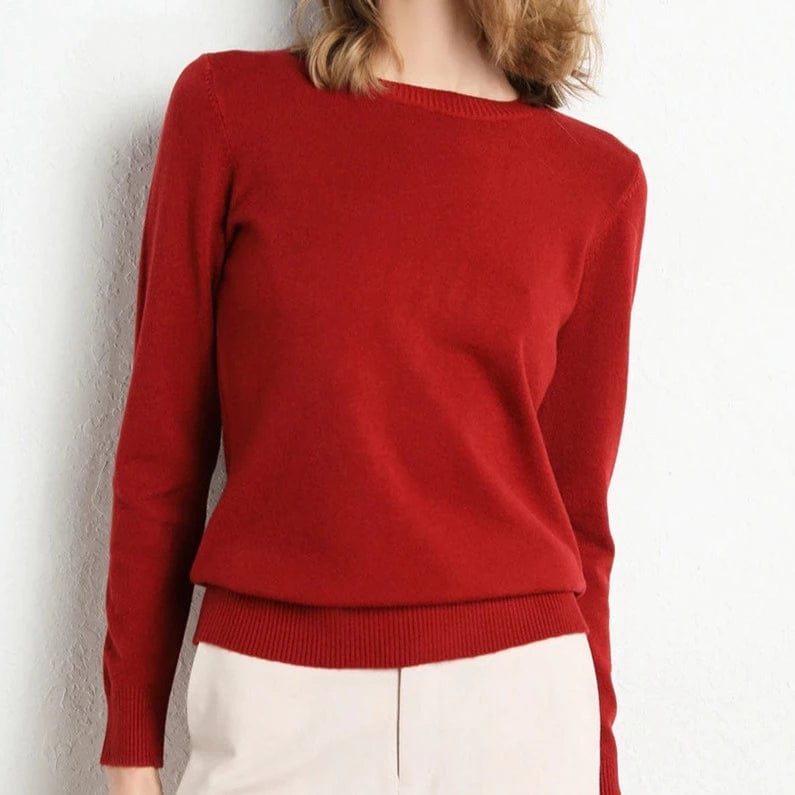 Pull rouge femme en laine, manches longues, col rond, porté avec un pantalon beige. Mode automne-hiver, style élégant et confortable.