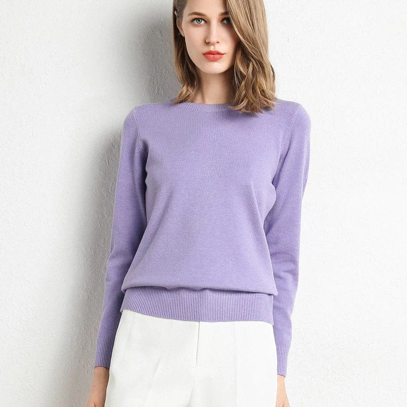 Femme portant un pull violet élégant, manches longues, col rond, assorti à un pantalon blanc. Mode féminine chic et moderne.