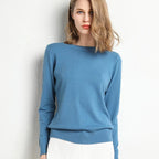 Femme portant un pull bleu élégant, manches longues, col rond, sur fond blanc. Mode féminine, tenue décontractée, style moderne.