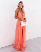 Femme en robe longue rose pêche élégante, tenant une pochette blanche. Mode féminine, style chic, tenue de soirée glamour.