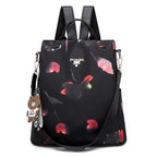 Sac à dos noir élégant avec motif floral abstrait, bretelles ajustables, porte-clés ours en peluche, idéal pour mode féminine et usage quotidien.