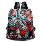 Sac à dos floral coloré avec motifs de feuilles rouges, bleues et beiges, design moderne et élégant, idéal pour la mode et le voyage.