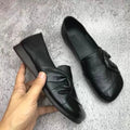 Chaussures en cuir noir pour femme avec nœud décoratif, semelle plate, design élégant et moderne, parfaites pour un style décontracté ou professionnel.