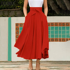 Robe longue rouge élégante avec ceinture nouée, portée par une femme debout devant un mur décoratif. Mode féminine, style chic, tendance été.