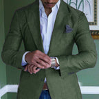 Homme en costume vert ajusté, chemise blanche, ajustant sa montre-bracelet argentée. Élégance masculine, mode formelle, style moderne.