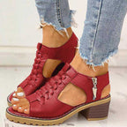 Chaussures rouges à talons blocs, ouvertes, avec fermeture éclair latérale, portées avec un jean déchiré. Mode femme, tendance chaussures été.