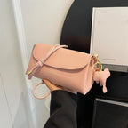 Sac à main rose en cuir texturé, design élégant avec fermeture à cordon, porte-clés en forme d'os, idéal pour mode féminine et accessoires tendance.