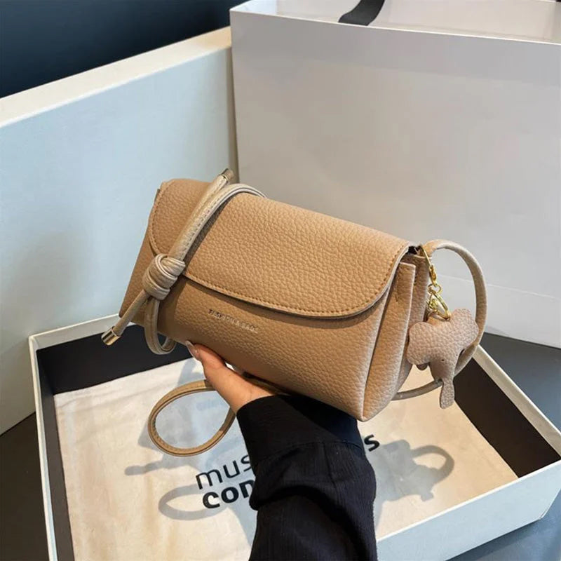 Sac à main en cuir beige dans une boîte, avec bandoulière et porte-clés en forme de cœur. Accessoire mode élégant et tendance pour femme.