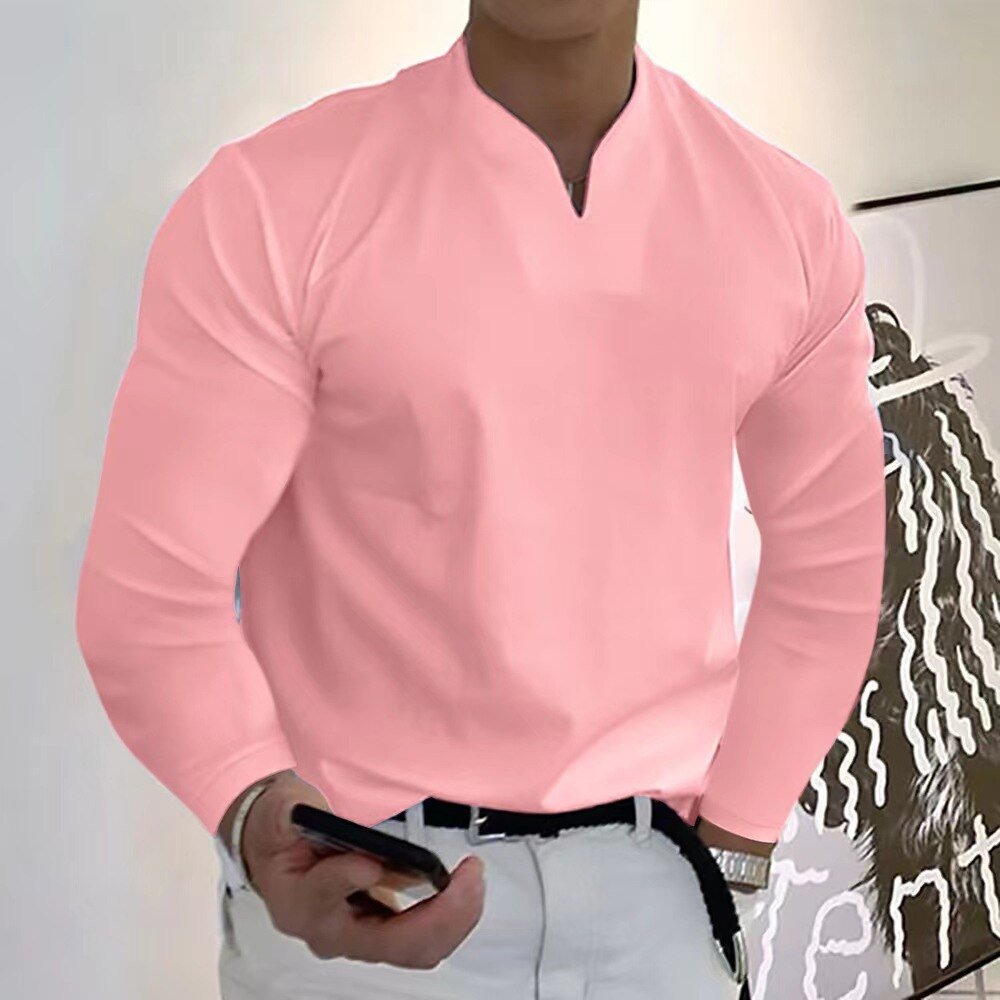Homme en chemise rose élégante, tenant un smartphone, debout devant une œuvre d'art moderne. Mode masculine, style décontracté chic.