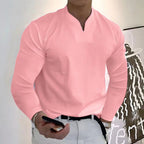Homme en chemise rose élégante, tenant un smartphone, debout devant une œuvre d'art moderne. Mode masculine, style décontracté chic.