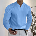 Homme en chemise bleue à manches longues, tenant un smartphone. Mode masculine élégante, tenue décontractée, style moderne.