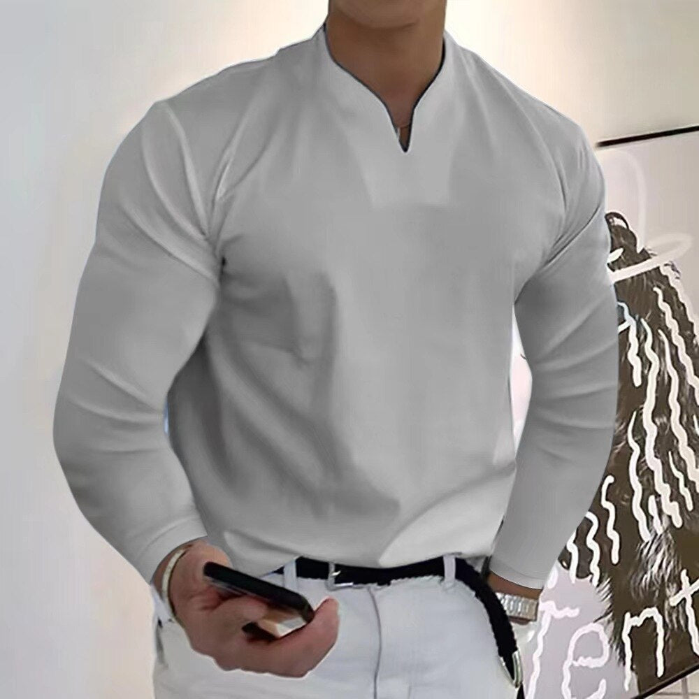 Homme en chemise blanche élégante, tenant un smartphone, debout devant une œuvre d'art moderne. Mode masculine, style contemporain.