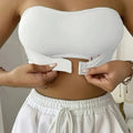 Femme ajustant un soutien-gorge bandeau blanc sans bretelles, vêtue d'un pantalon blanc. Mode féminine, lingerie confortable, style estival.