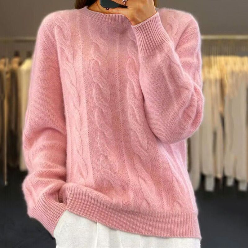 Pull rose en laine torsadée, manches longues, col rond, porté par une personne. Mode automne-hiver, vêtement chaud et confortable.