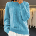 Pull bleu en laine torsadée, manches longues, porté par une personne. Mode automne-hiver, style décontracté, fond de dressing moderne.