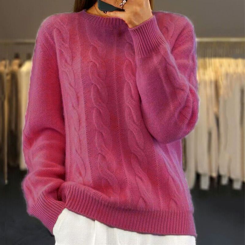 Pull rose en laine torsadée, manches longues, porté par une femme dans un magasin de vêtements. Mode automne-hiver, style décontracté et élégant.