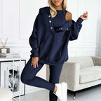 Femme en ensemble de survêtement bleu marine, style décontracté, avec épaules dénudées, posant dans un salon moderne. Mode féminine tendance.
