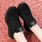 Chaussures de sport noires sur fond de gravier rouge, design respirant, lacets noirs, semelle antidérapante. Idéales pour la course et le fitness.